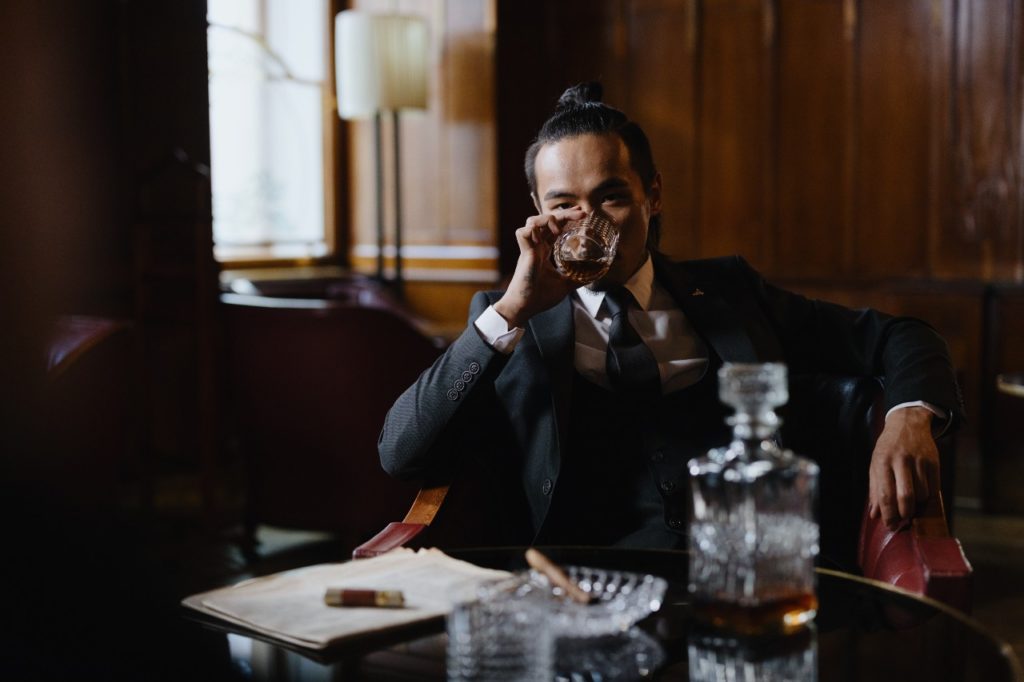 man drinking whiskey with a decanter